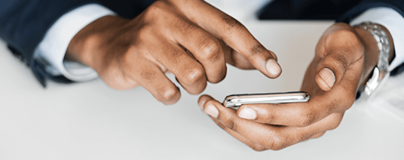 A man in a suit is using a cell phone for mobile learning.