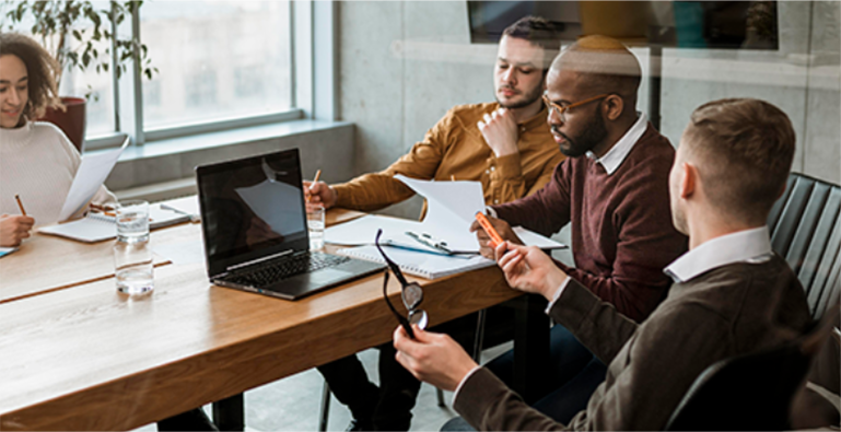 A group of people sitting around a table in a meeting discussing industry trends.