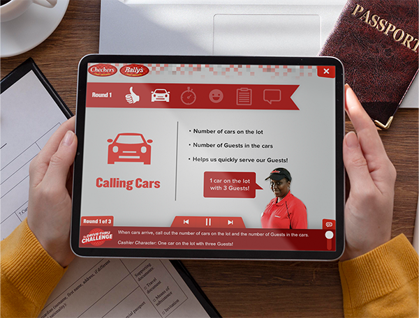 A person using a tablet with an interactive learning games service simulation game displayed on the screen, featuring a character and instructions on managing a car lot.