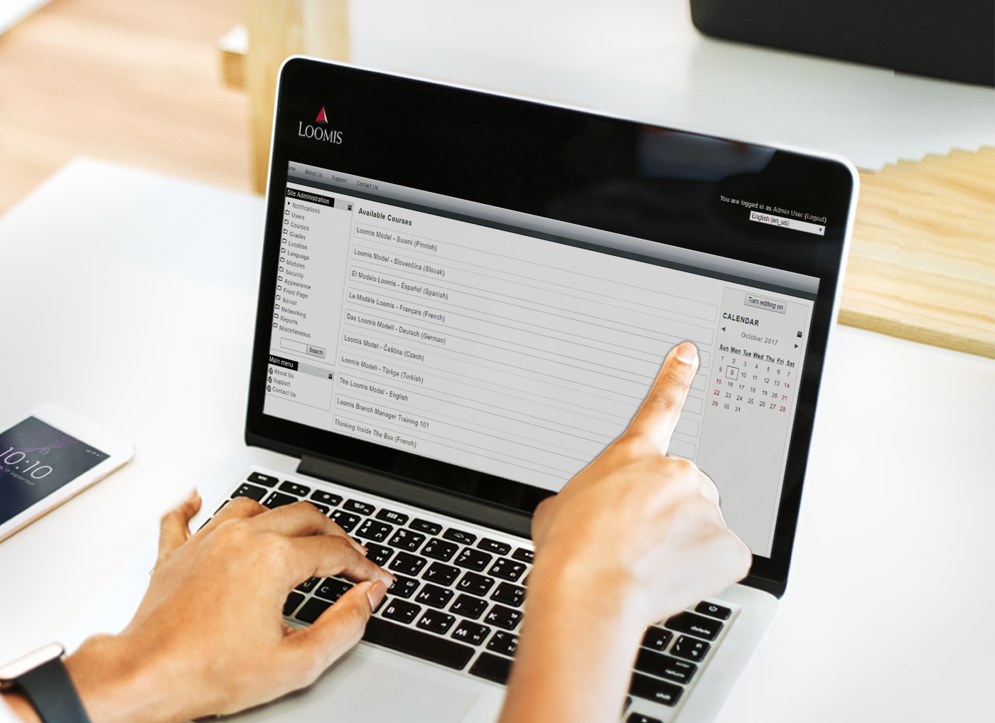 Person using a laptop displaying a Custom Learning Management System vendor's spreadsheet application with data tables while pointing at the screen.