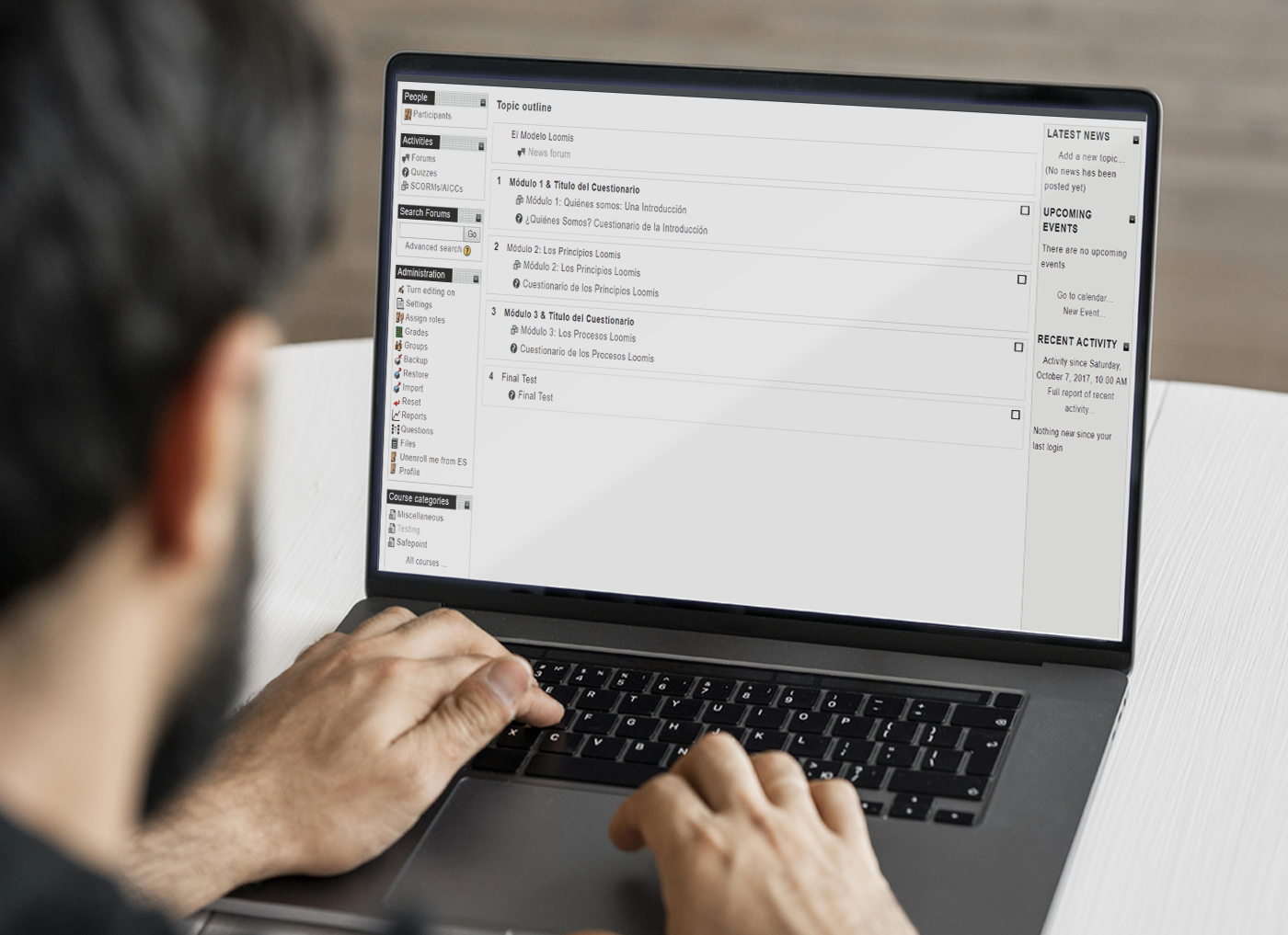 Man working on a laptop with an email inbox from a Custom Learning Management System vendor displayed on the screen.