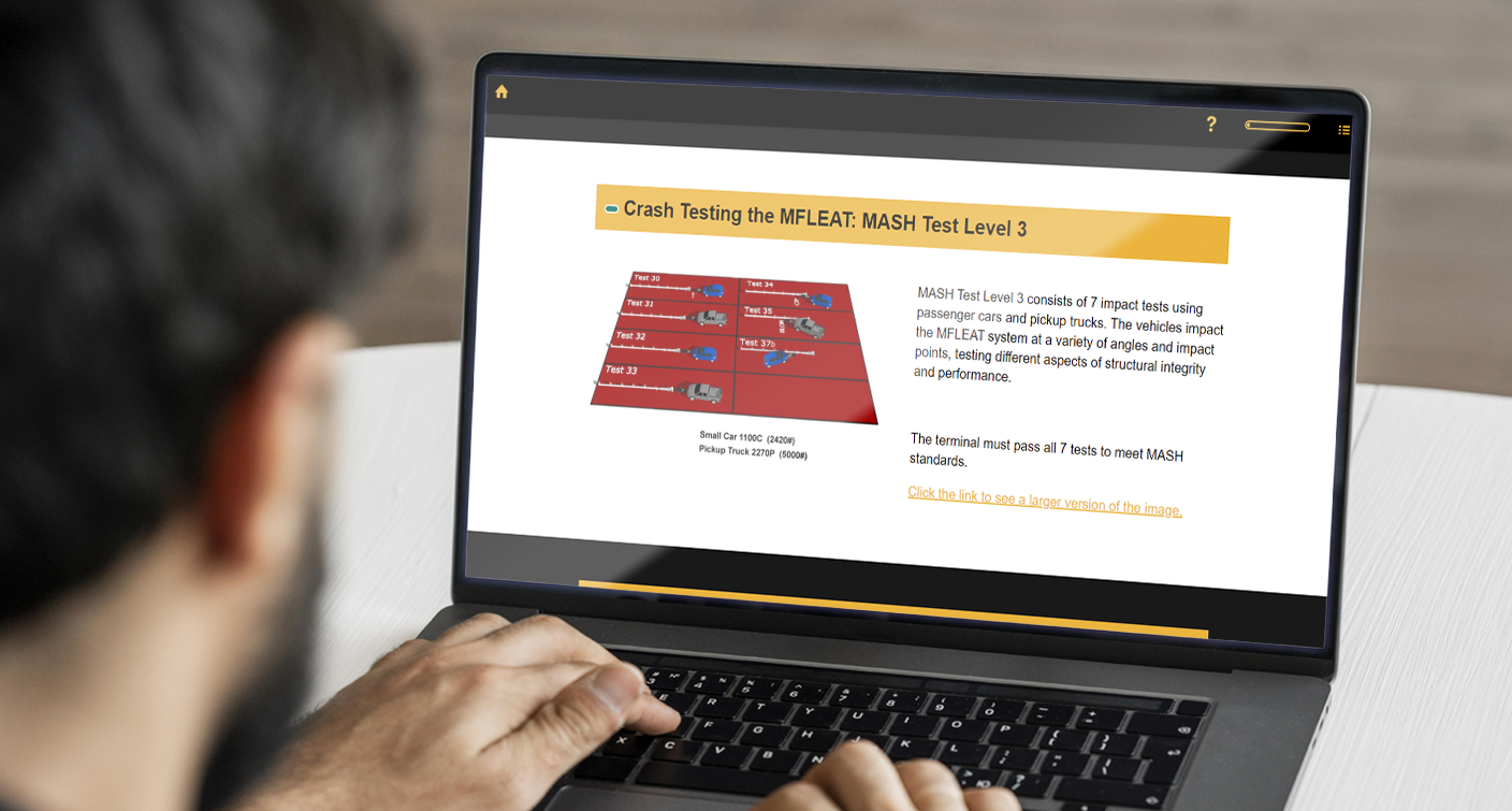 Designing Digitally - A person is using a laptop, viewing a webpage titled "Crash Testing the MFL-EAT: MASH Test Level 3" featuring an illustration and text about vehicle impact tests, part of a guard rails product training simulation. Designing Digitally -