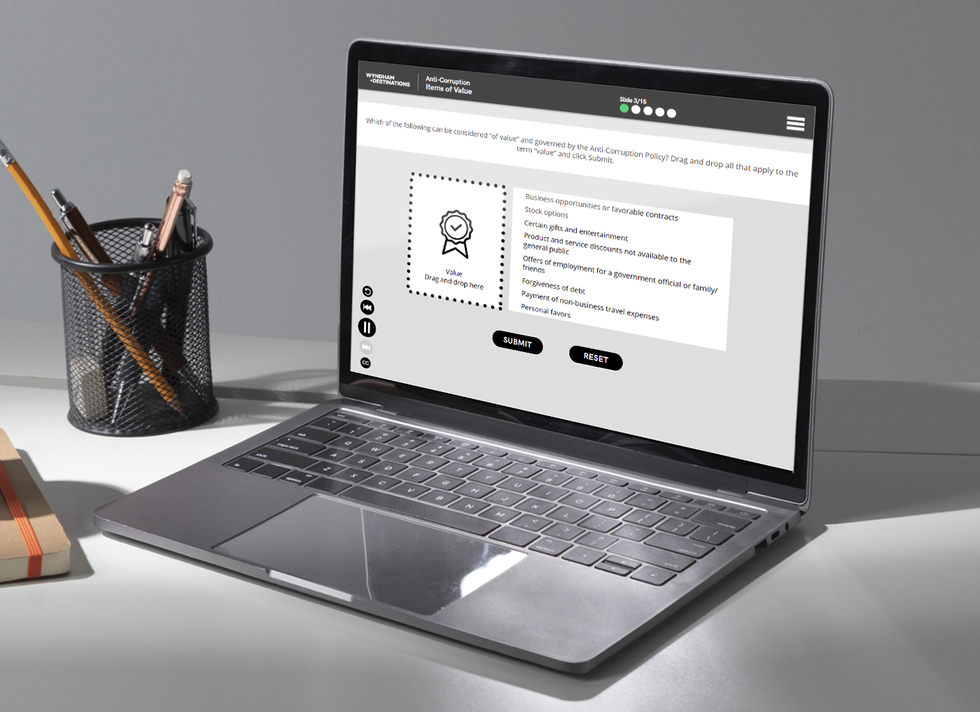 Designing Digitally - Laptop on a desk displaying an online form for the Compliance Training Program. A pen holder with pencils and a notebook are placed beside it. The workspace is well-lit with natural light. Designing Digitally -