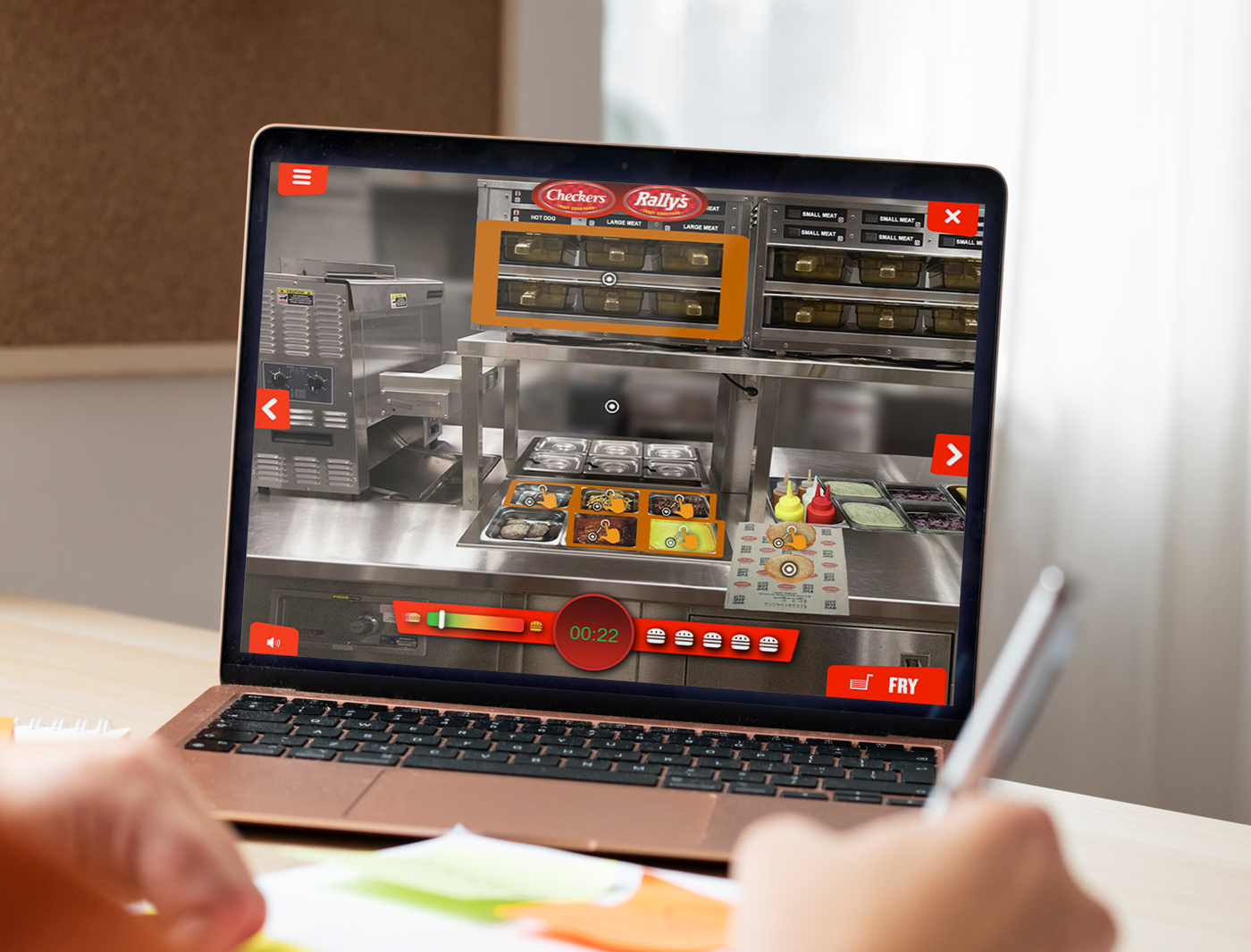 A person playing custom training games for employees in a fast food restaurant simulation on a laptop.