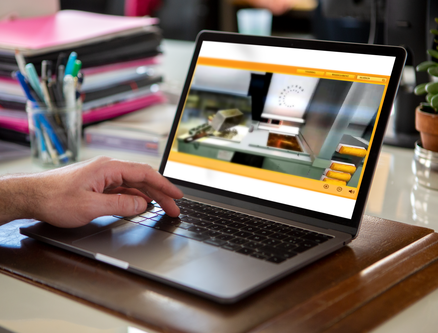 A person using a laptop on a wooden desk with fast food training simulations and office supplies in the background.