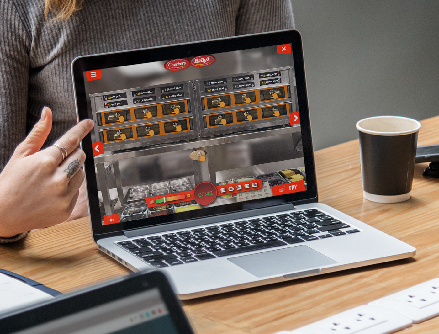 Designing Digitally - Person playing an online slot machine game on a laptop screen, with a coffee cup beside it on a desk in an office, engaged with virtual reality equipment. Designing Digitally -