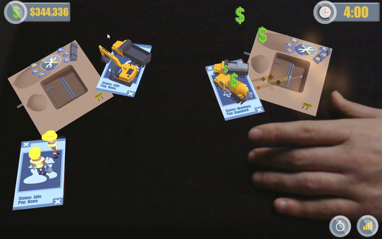 Person interacting with augmented reality training games involving construction equipment and characters displayed over a real-world surface.