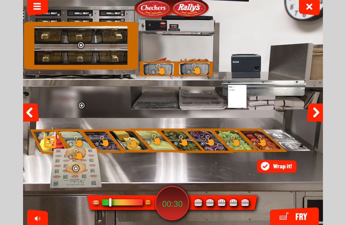 Commercial fast food kitchen with sandwich assembly line, warming ovens, and custom training games for employees.