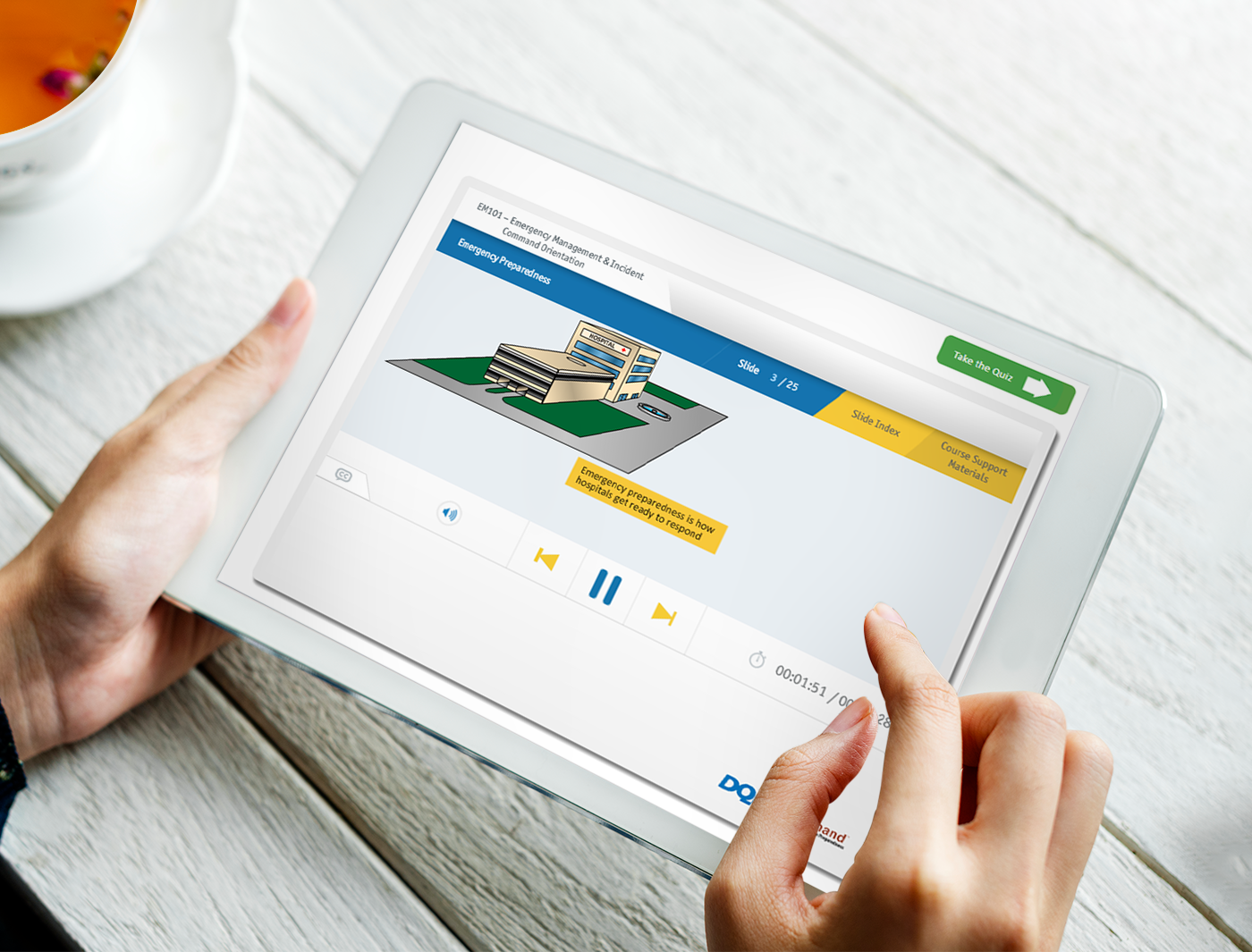 Designing Digitally - Hands holding a tablet displaying an online training vendor's e-learning interface about financial education, with icons and text on screen. Designing Digitally -