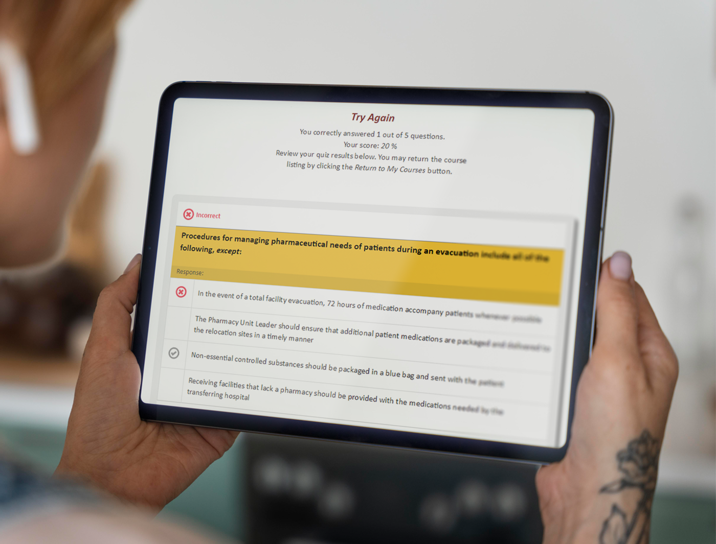Designing Digitally - A person holding a tablet displaying an eLearning tutorial with text about pharmaceutical needs during an evacuation. Designing Digitally -