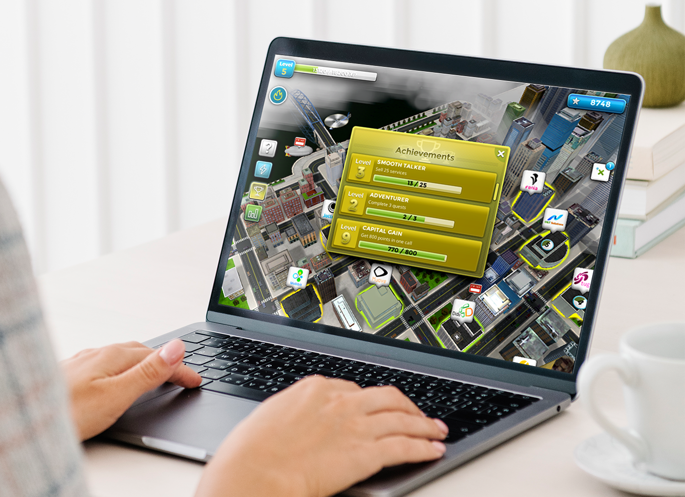 Designing Digitally - A person using a laptop displaying a city-building simulation game with an achievements pop-up window, designed by an eLearning vendor. Designing Digitally -