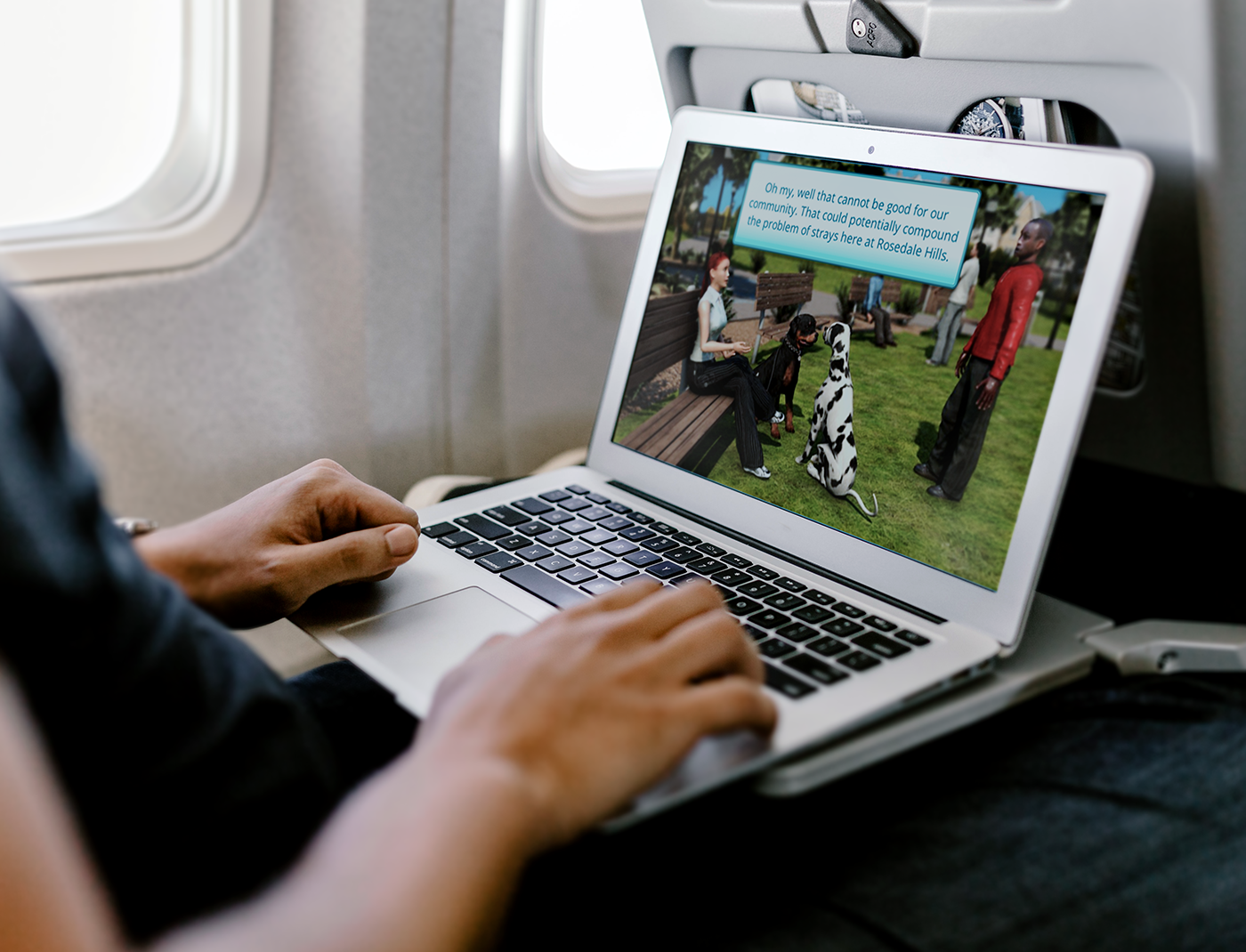 Designing Digitally - A person is using a laptop on an airplane, with an image of people and a dog in a park displayed on the screen, likely engaging in pet ownership training simulations. Designing Digitally -