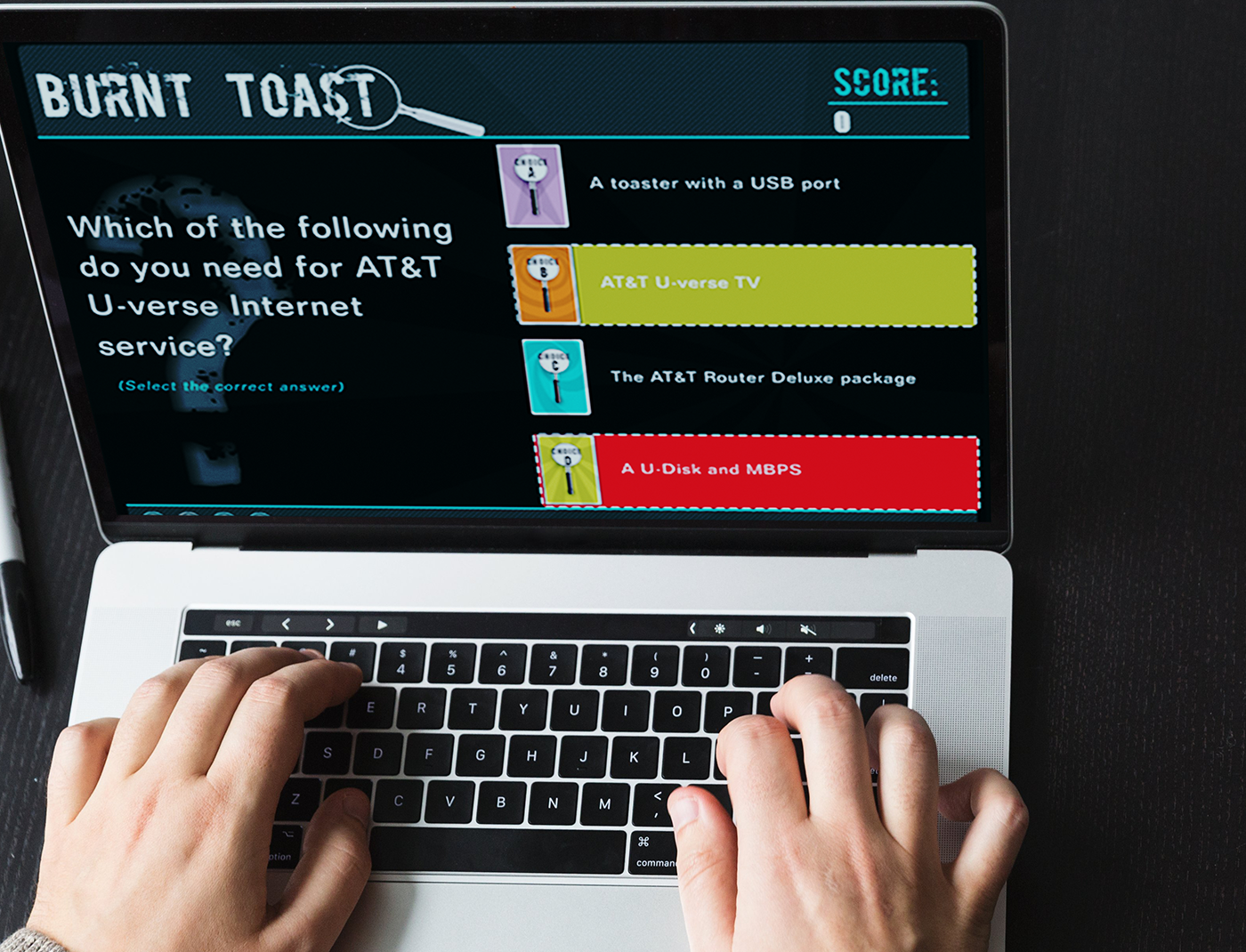 Designing Digitally - A person is playing a quiz game called "Burnt Toast" on a laptop, facing the question: "Which of the following do you need for AT&T U-verse Internet service?" along with multiple choice answers. Interestingly, this simulation feels as engaging as Trauma Nurse Training Simulations. Designing Digitally -