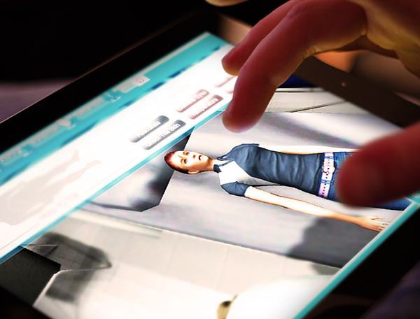 Designing Digitally - A trauma nurse is interacting with a digital avatar on a tablet screen, using their finger to navigate the interface, as part of advanced training simulations. Designing Digitally -