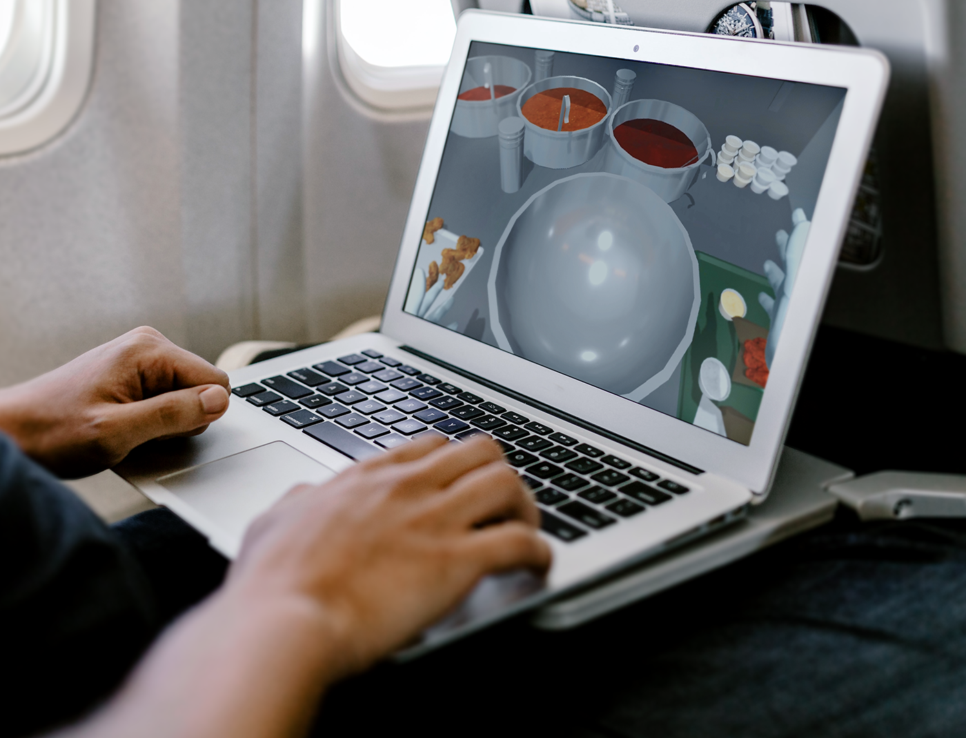 Designing Digitally - A passenger immerses themselves in a cooking simulator game on their MacBook while cruising at 30,000 feet, perfecting their food preparation training. Designing Digitally -