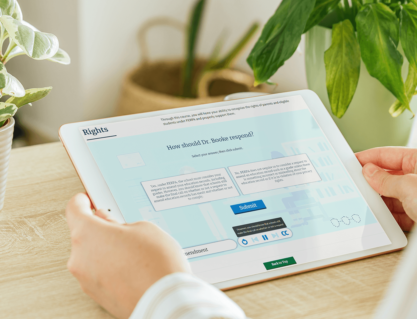 Designing Digitally - A person holds a tablet displaying an interactive online course on ethical decision-making for healthcare professionals, featuring text prompts and response options. Green plants are visible in the background, enhancing the scene. The course includes Occupational Therapy Simulations to enrich learning experiences. Designing Digitally -