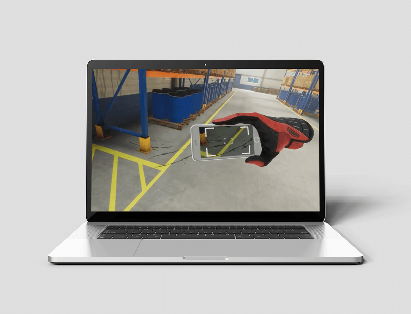 A laptop displaying an augmented reality application with a virtual red glove interacting with a real-world industrial environment.