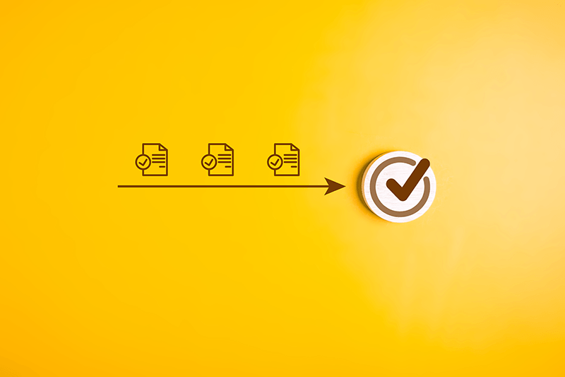 Designing Digitally - Diagram showing a linear progression of three documents with checkmarks leading to a larger checkmark inside a circle on a yellow background, representing the streamlined process in our Custom Learning Management System. Designing Digitally -